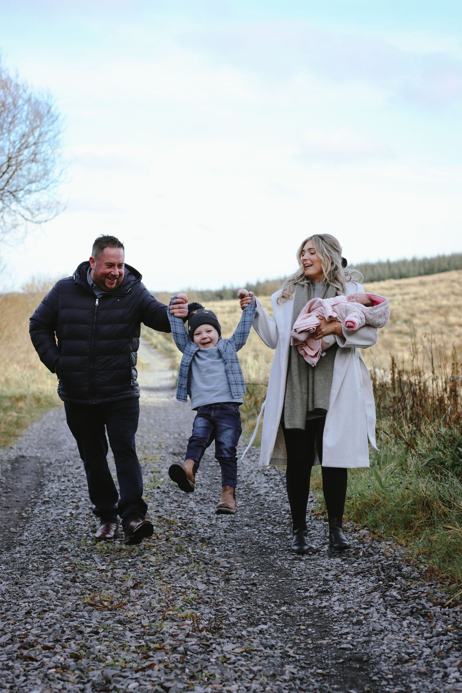 Family enjoying a walk on a country path with their young children on an autumn day.