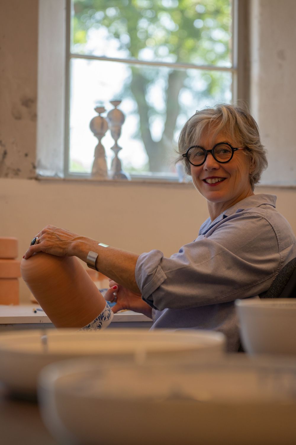 Coby Art van Buuren, ontspannen aan het werk, ze schildert op keramiek volgens traditionele plateel kunst. Portret door Martine Vonk