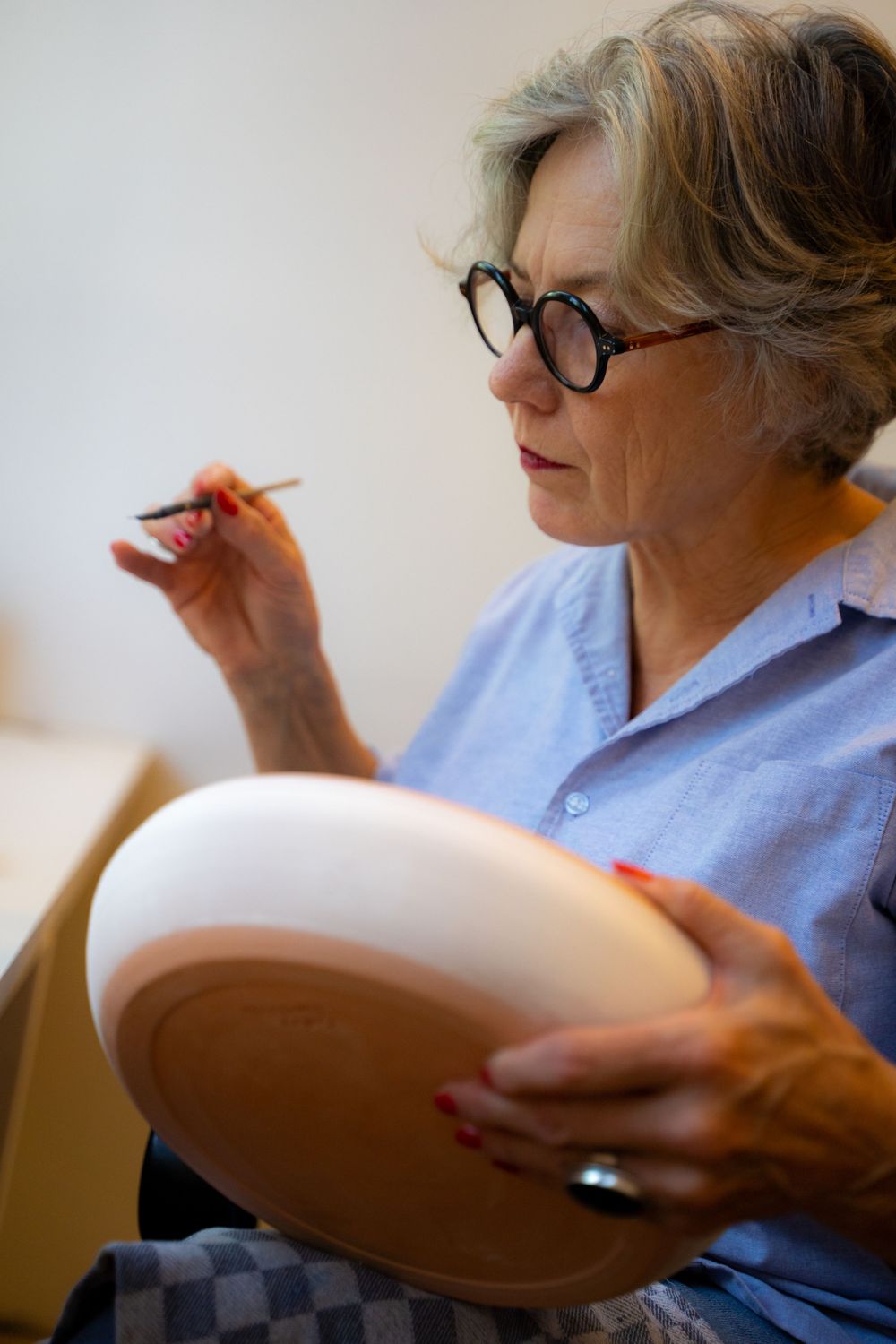 Art van Buuren, werkt op keramiek aan haar blauwe plateel schilderkunst. Portret door Martine Vonk