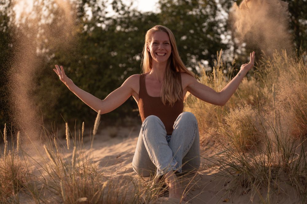 Vrolijke en ontspannen Tamara van Well, Yoga coach tijdens golden hour shoot in duinzand. Portret door Martine Vonk