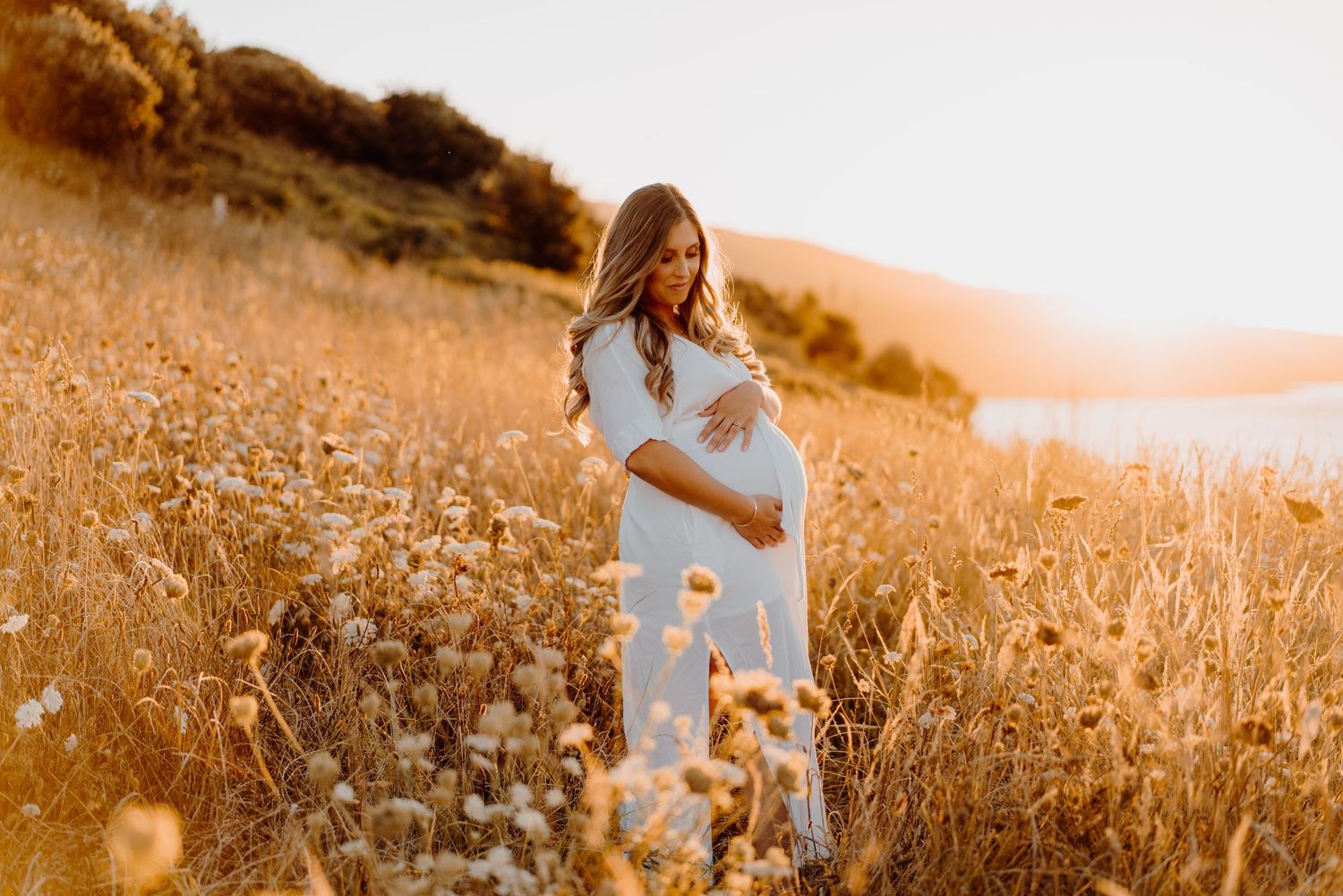 Woman holding her belly during a sunset maternity photoshoot