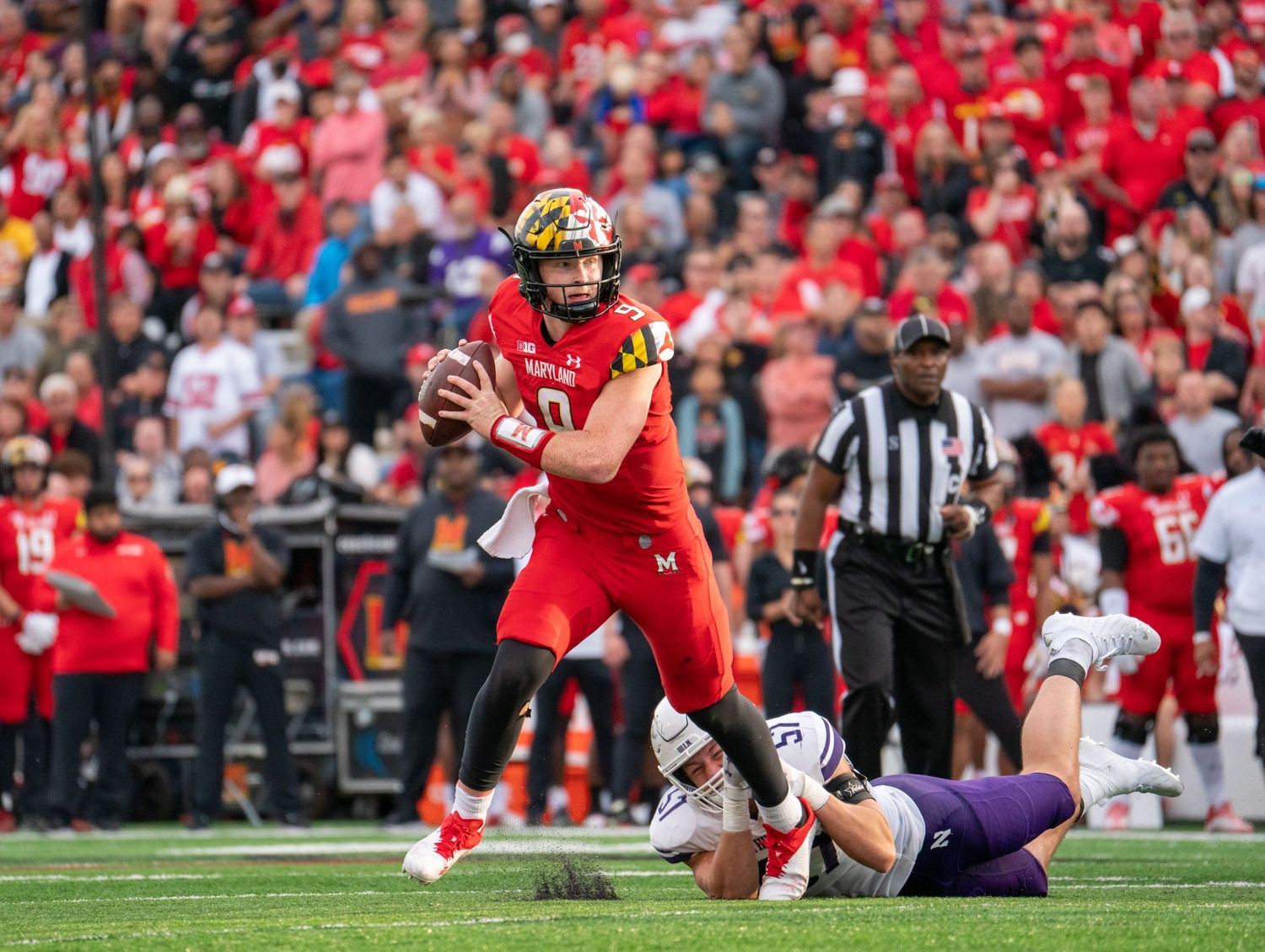 Football players in red uniforms competing during an intense game at a packed stadium.
