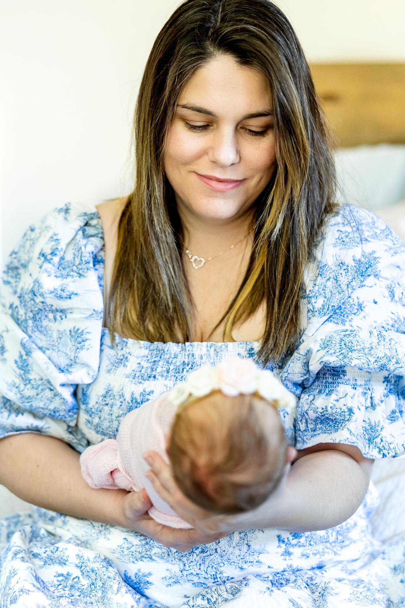 Mom holds her new baby girl and smiles down at her during lifestyle newborn photos in Colorado Springs.