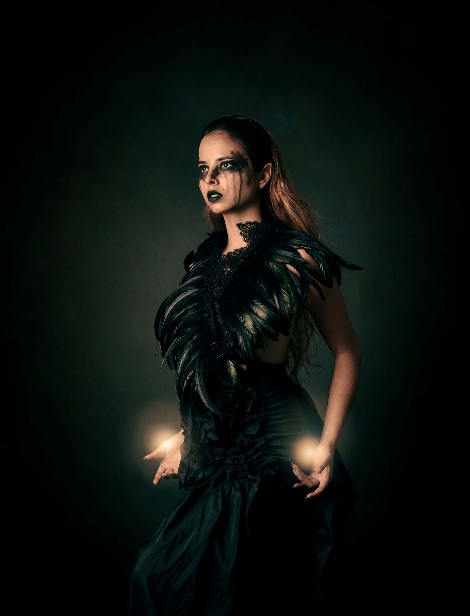Dark and dramatic portrait featuring a black feathered costume and moody lighting.