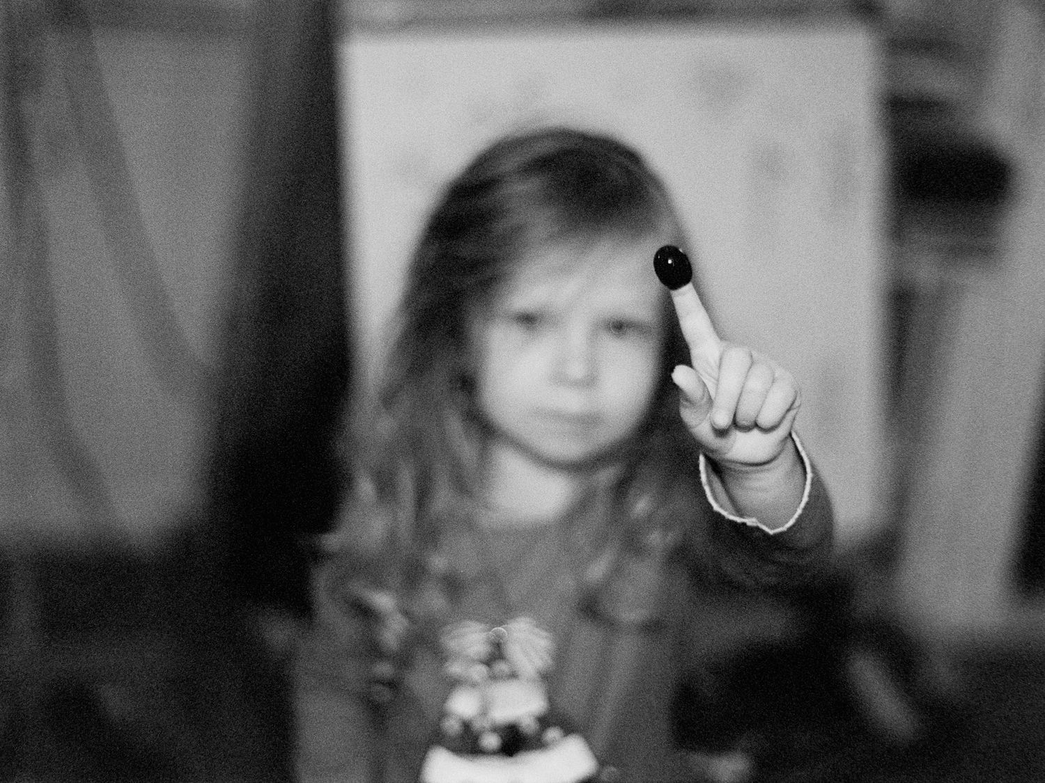 Black and white portrait of a small child holding up one finger.