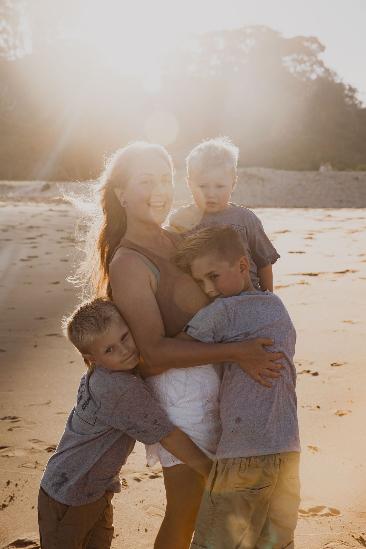 A joyful group hug on the beach at sunset creates a heartwarming scene.