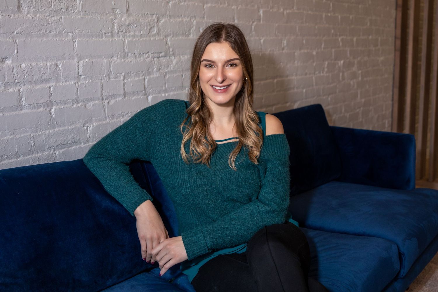 Woman relaxes on navy blue couch in casual green sweater.