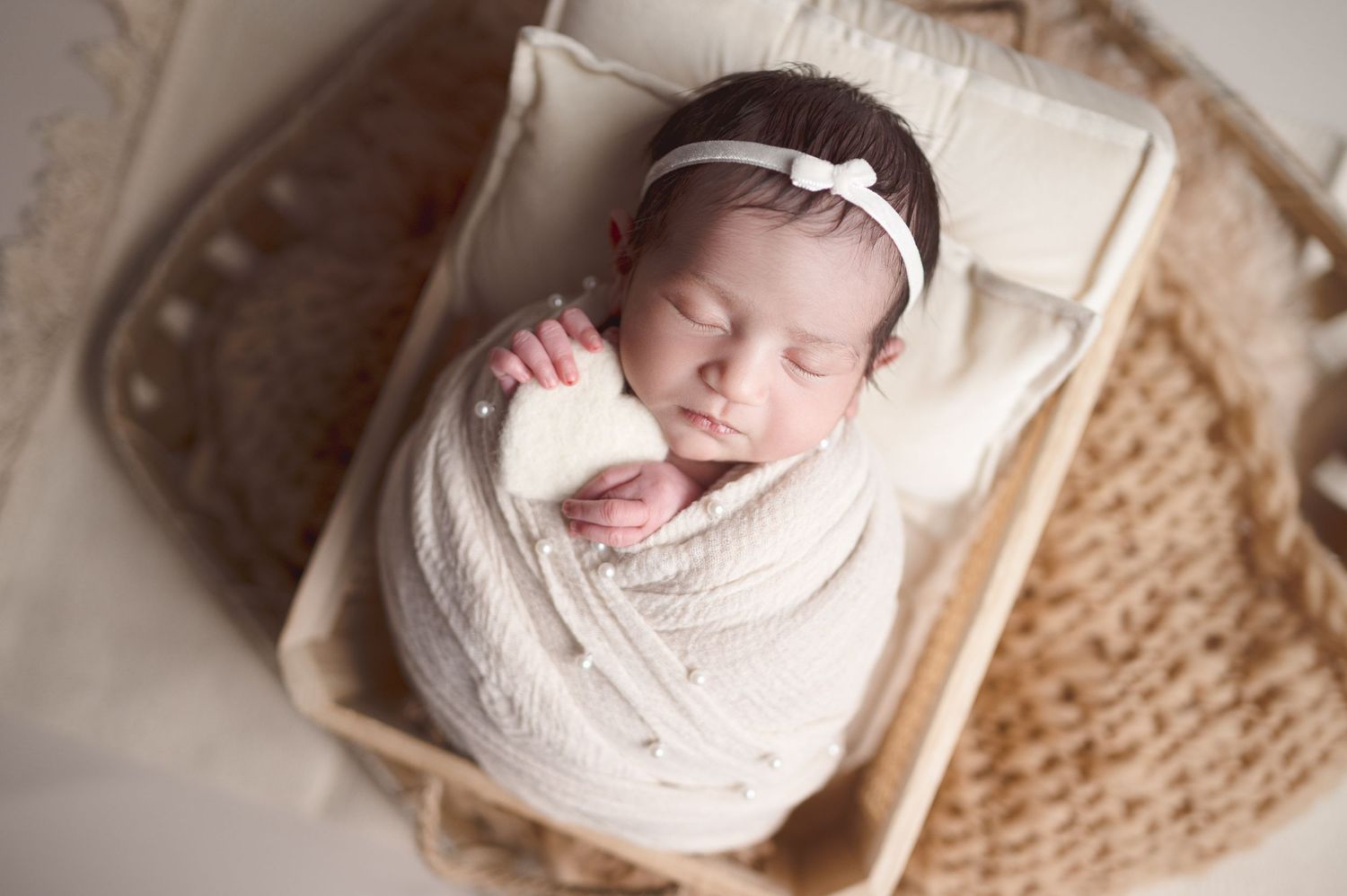 Sleeping newborn in white wrap photographed from multiple angles on neutral background.