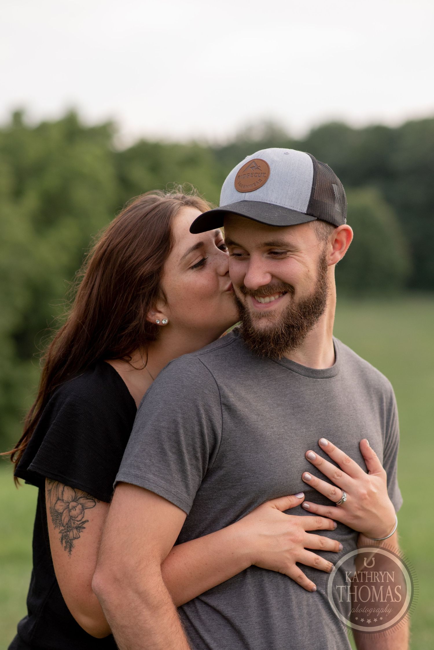 A couple sharing a sweet moment outdoors with one wearing a trucker hat.