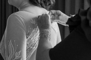 Close-up view of a delicate white lace wedding dress bodice with intricate beading detail and bangles.