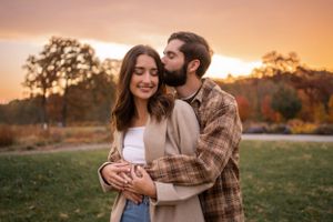 Couple embracing in autumn field during golden sunset.