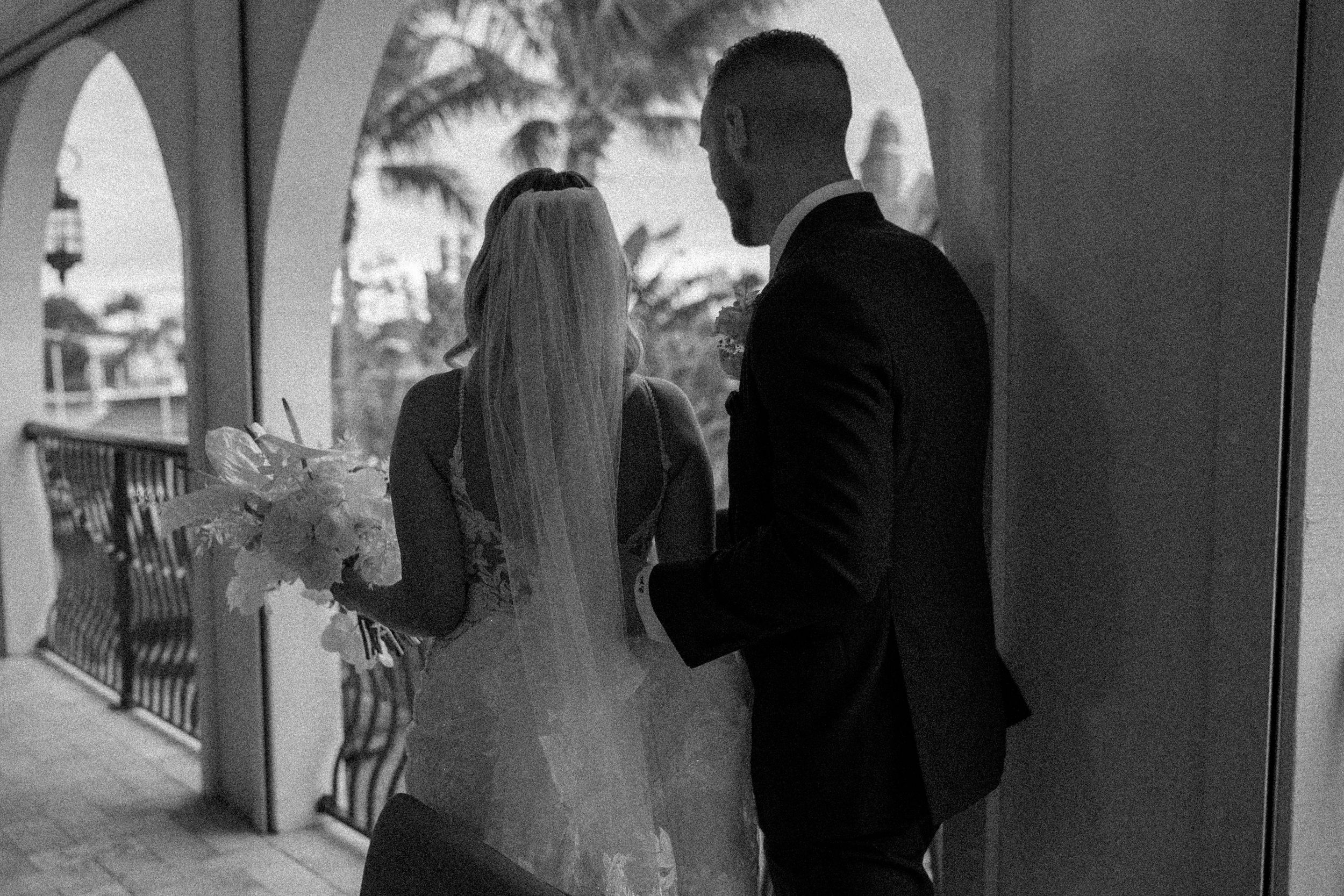 Romantic silhouette of a couple standing under an archway at golden hour.