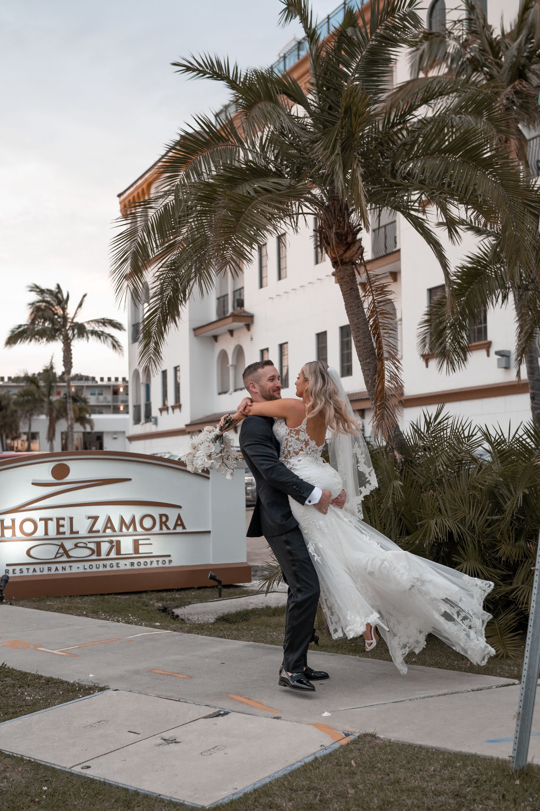 Couple dancing outside Hotel Zamora with palm trees swaying in the background.