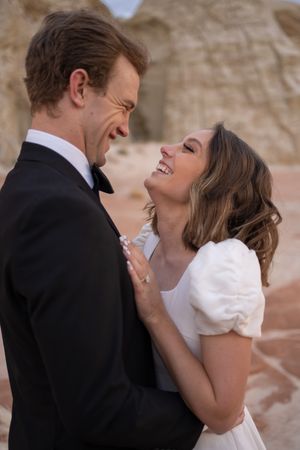 Joyful couple laughing together in front of desert rock formations.