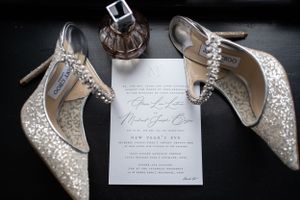 Wedding invitation and sparkly bridal shoes styled with perfume bottle.