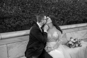 Black and white portrait of newlyweds sharing an intimate moment on outdoor stone steps.