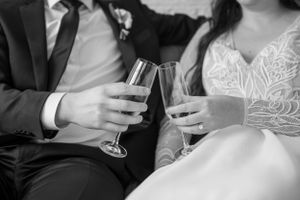 Close-up shot of champagne glasses held by couple in wedding attire.