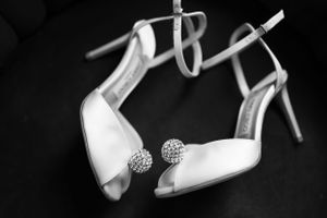White bridal shoes with crystal embellishments photographed against dark background.