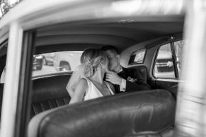 Black and white vintage car interior shot capturing intimate wedding moment.