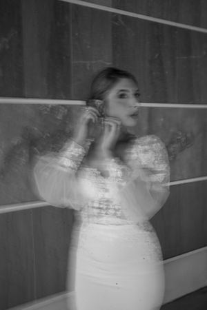 Artistic double exposure of bride adjusting earrings in black and white.