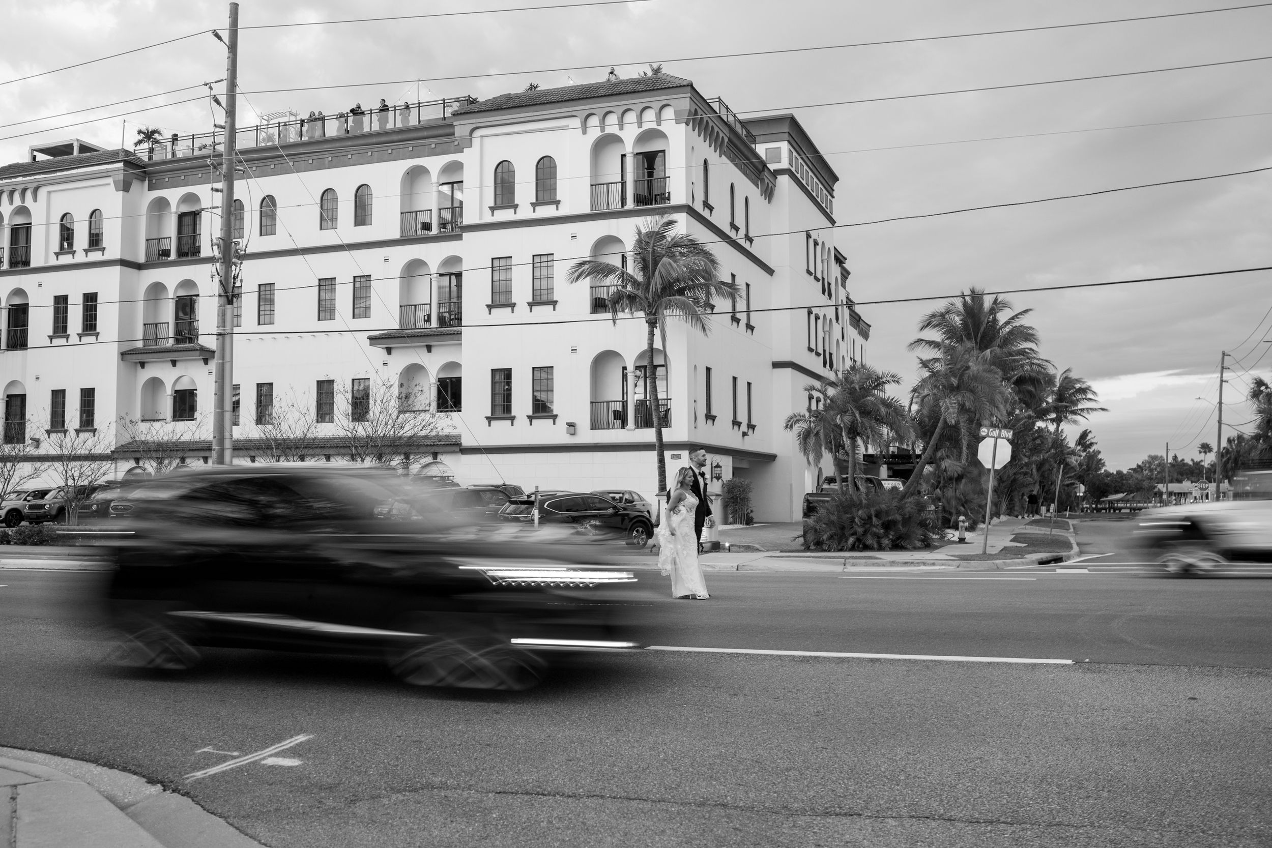 Vintage-style black and white photo of a historic building with a blurred car passing in the foreground.