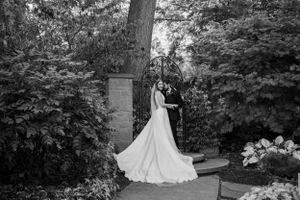 Elegant wedding photo of a white dress against lush garden greenery in black and white.