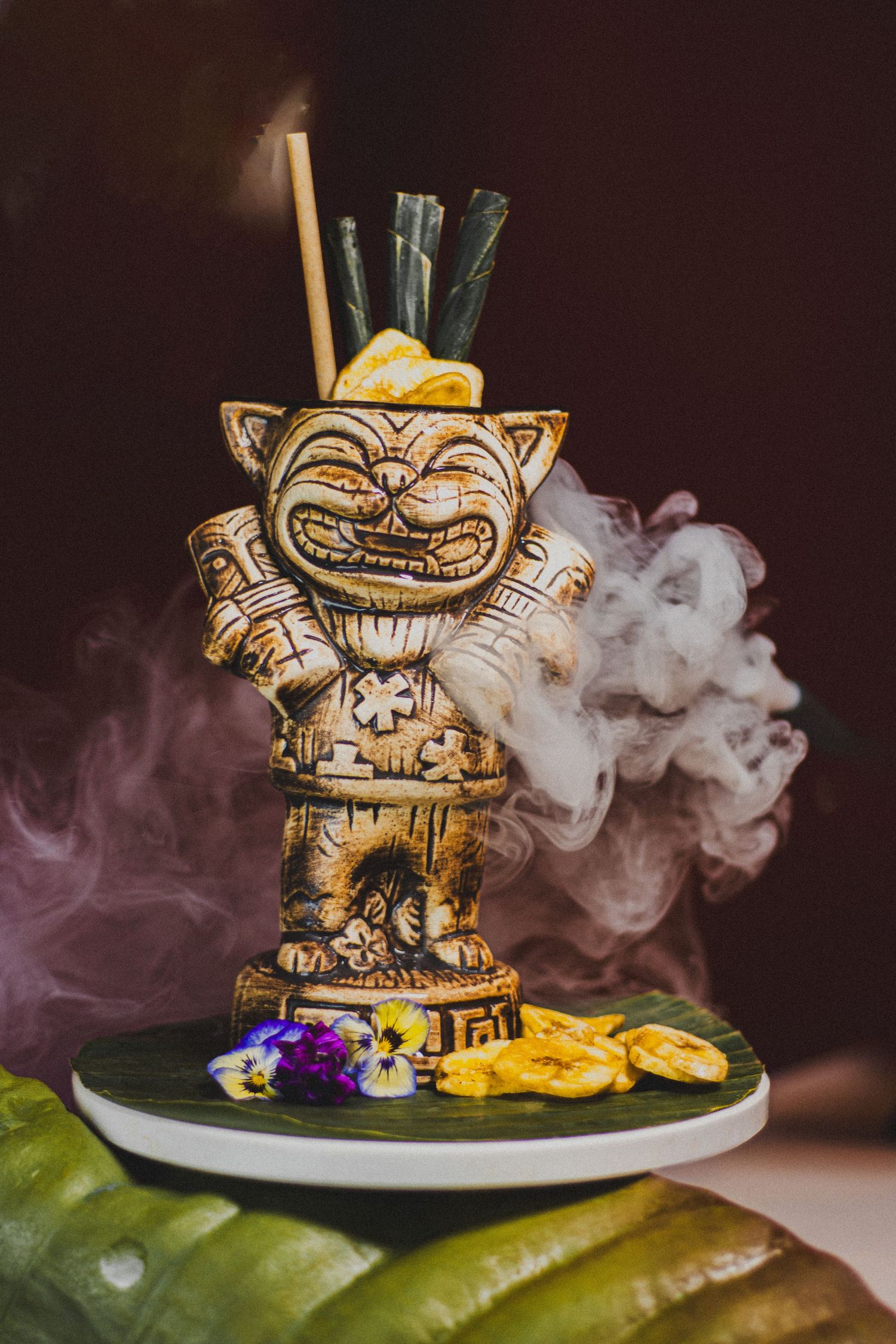 Creatieve Tiki-cocktail geserveerd in een decoratief glas met rook-effect en tropische garnering.