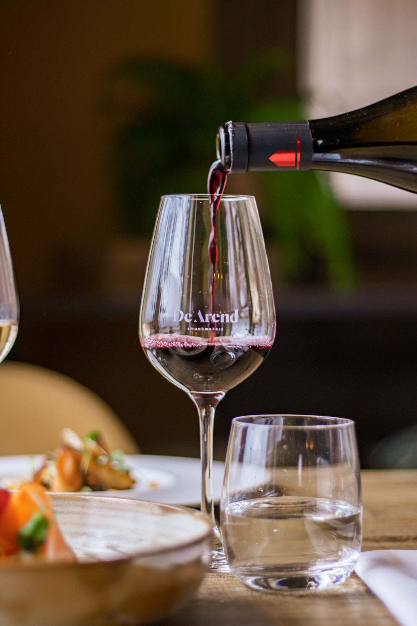 Rood wijn wordt ingeschonken in een elegant glas, onderdeel van een horeca shoot met focus op beleving