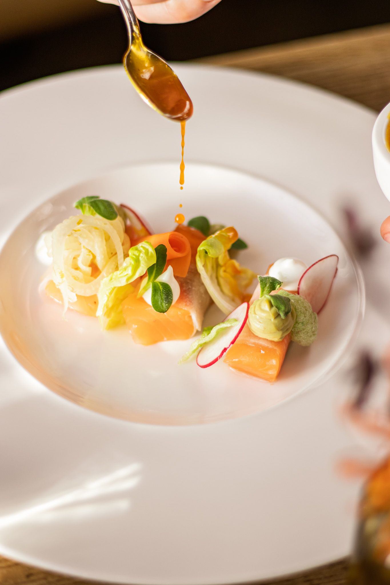 Saus wordt over een zalmgerecht gegoten voor een verfijnde presentatie in culinaire fotografie.