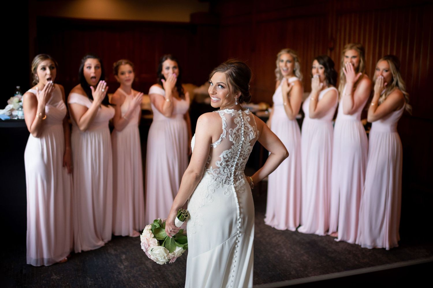 Bride giving over the shoulder look with bridesmaids lined up in background.