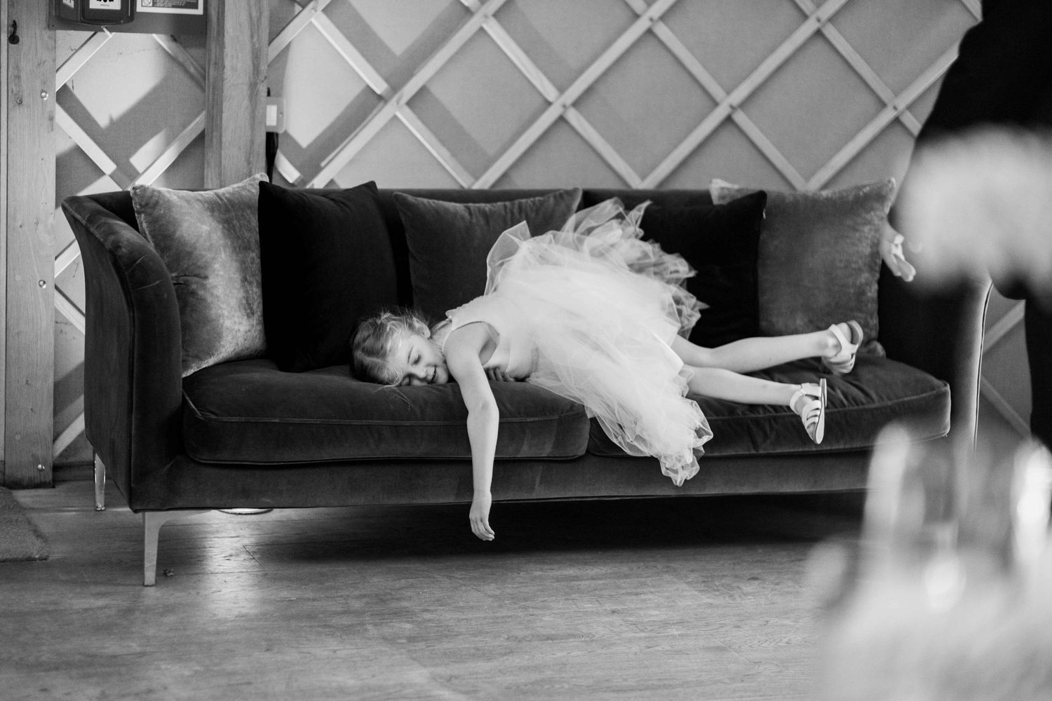 A young bridesmaid at the wedding lying playfully on a sofa