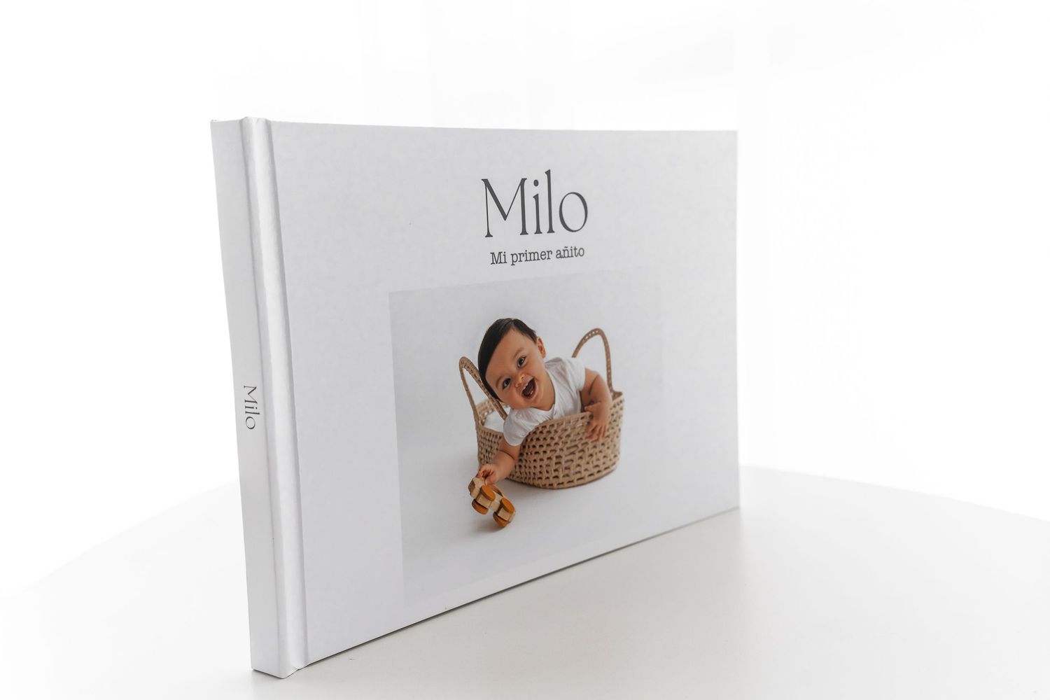 White photo album book with 'Milo' text and baby portrait on the cover.