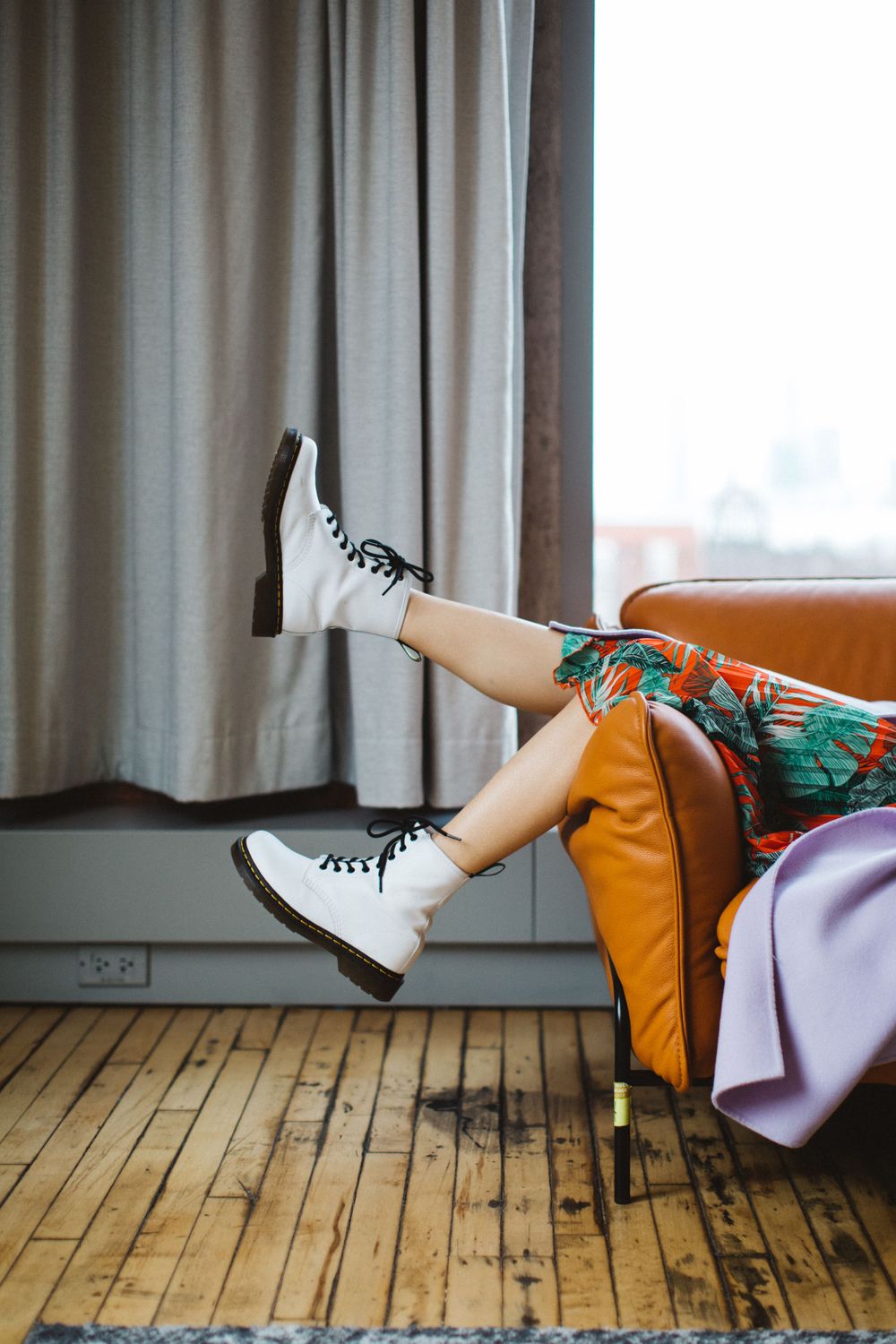 White combat boots propped up on orange couch with floral print clothing visible.