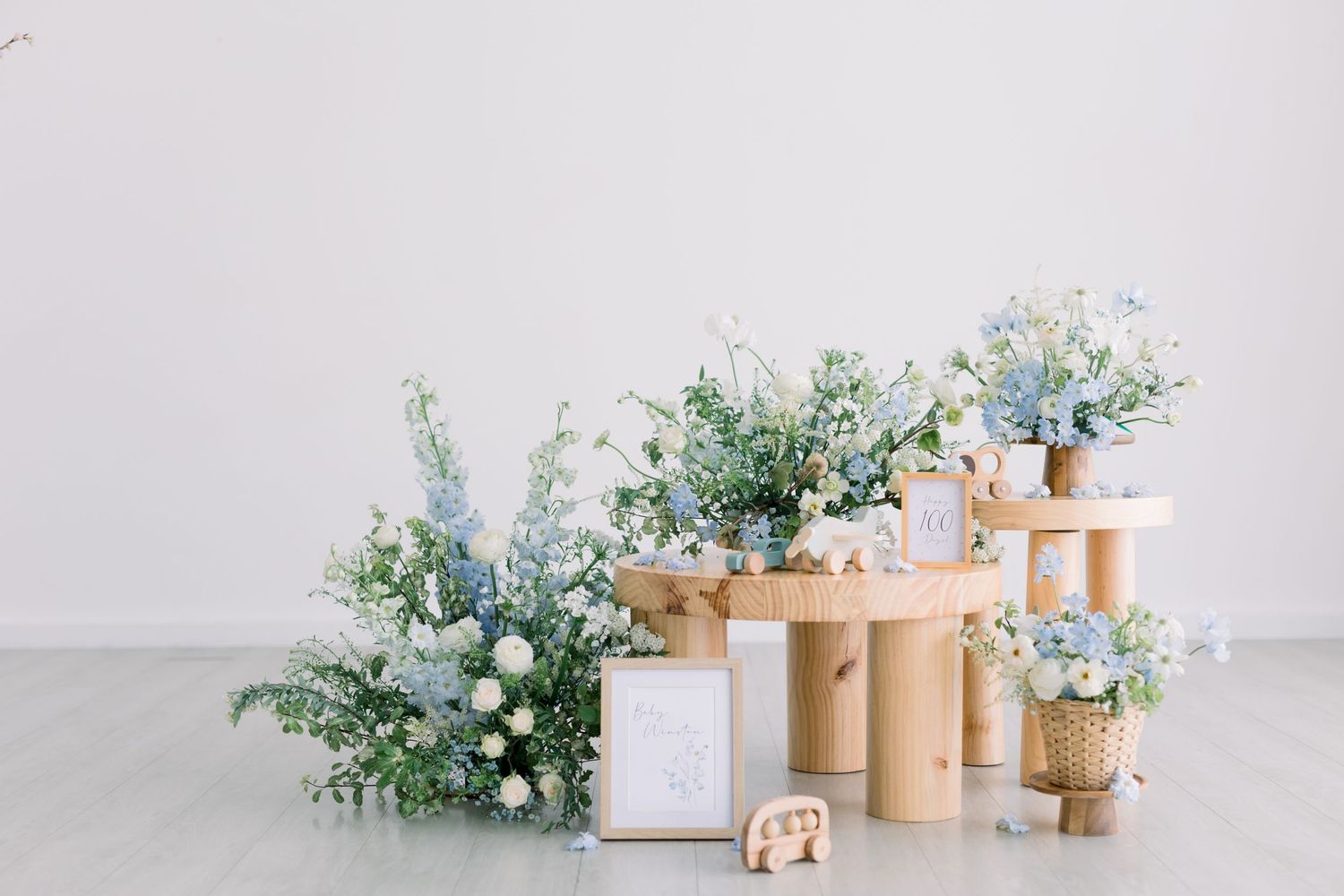 Elegant floral arrangement with blue and white flowers on wooden pedestals.