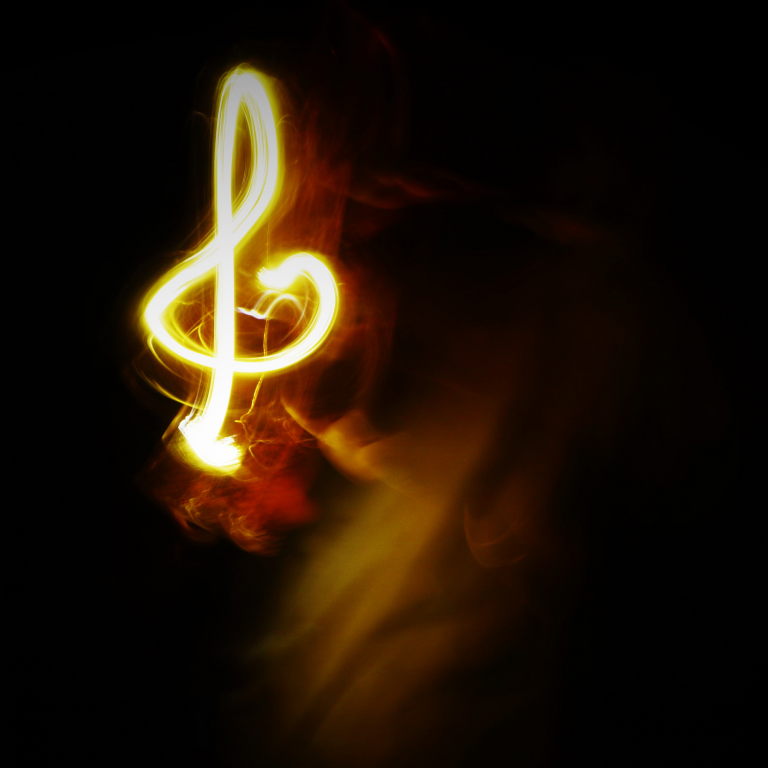 Light painting photography showing glowing musical notes against black background.