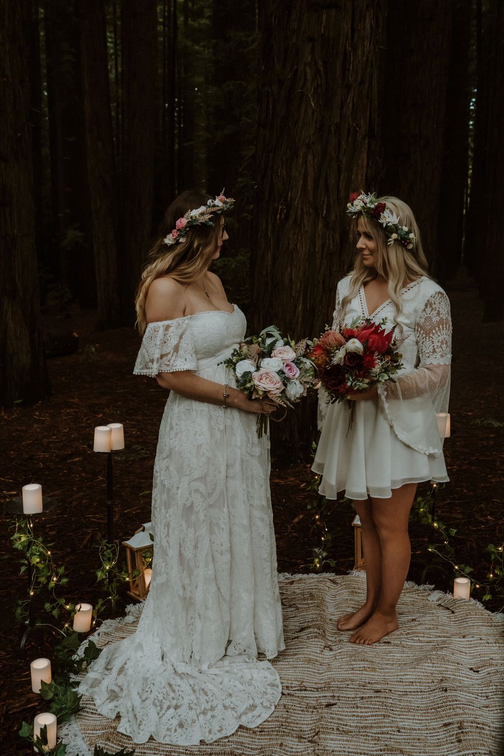 A romantic forest wedding setup features white dresses and glowing candles.