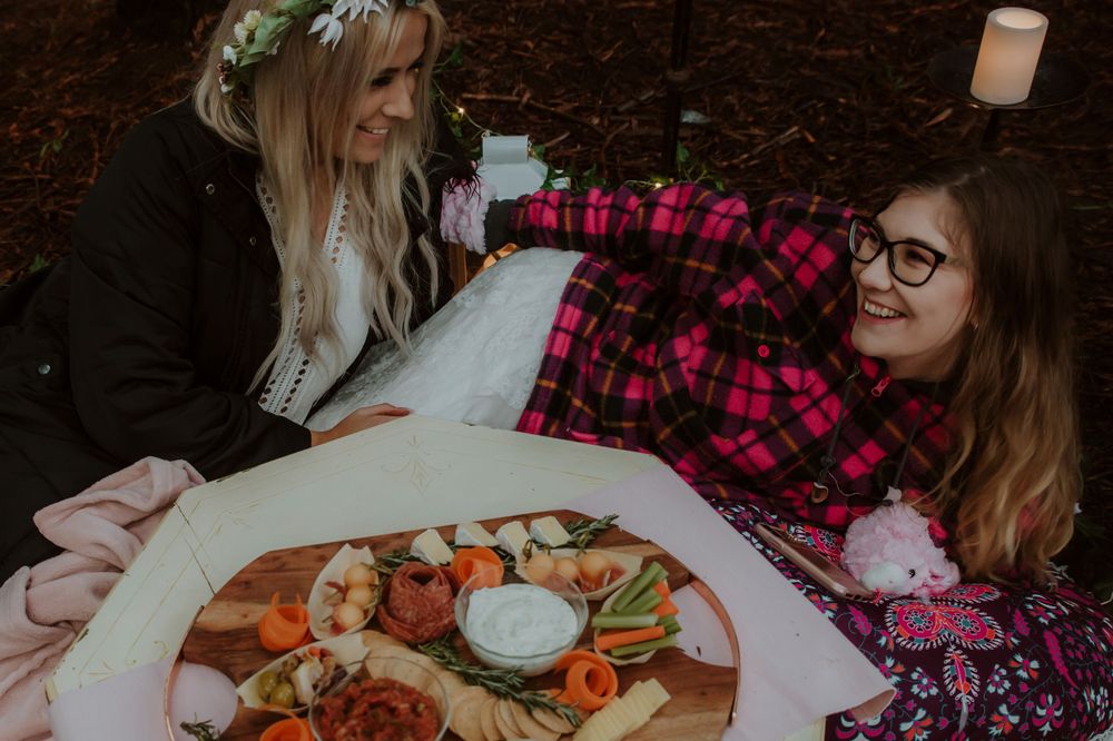 People sharing appetizers and snacks on a white plate at an outdoor gathering.