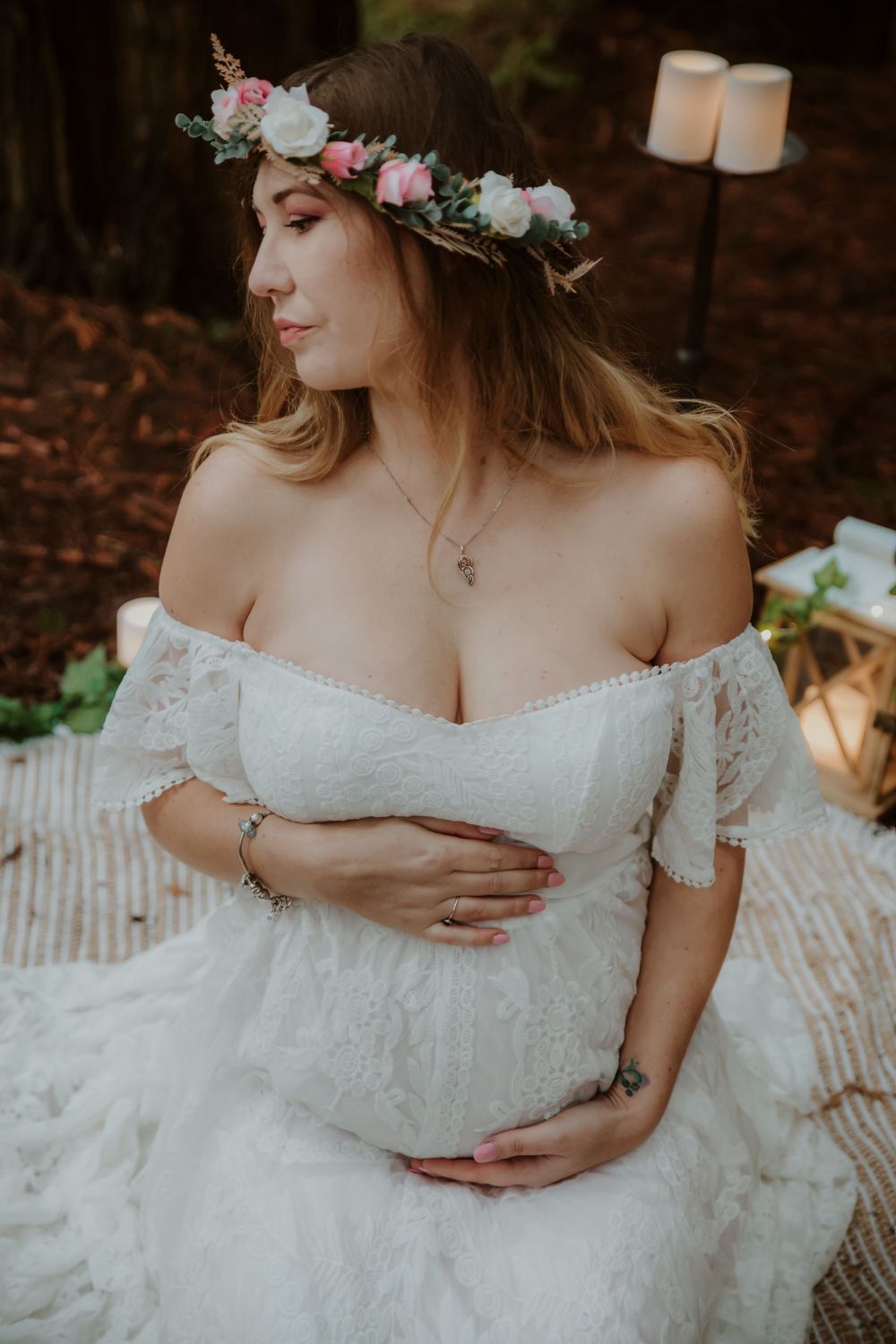 A romantic off-shoulder white lace dress with floral crown in a forest setting.