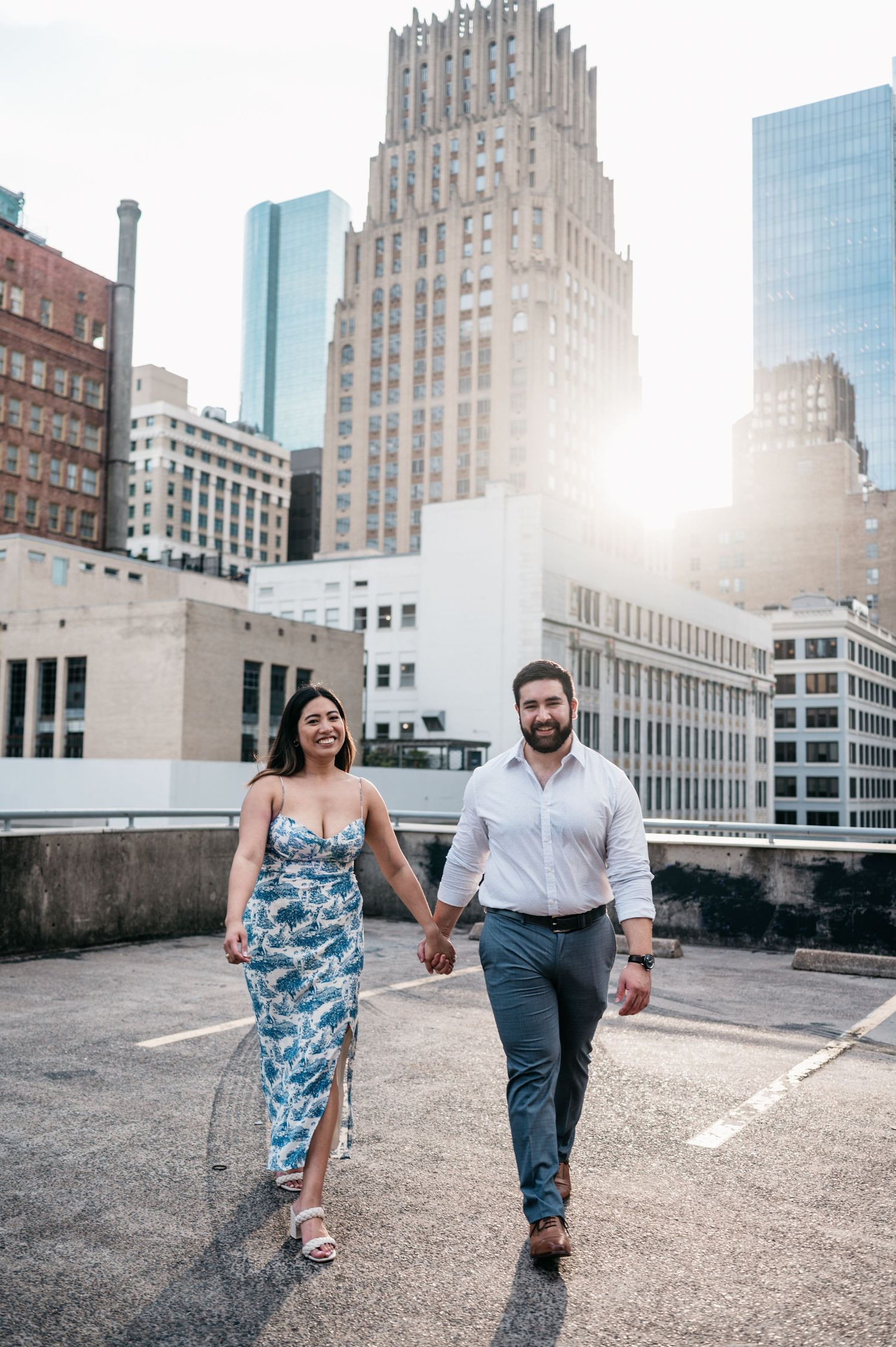 Couple walking on urban rooftop with art deco architecture and modern buildings in background.