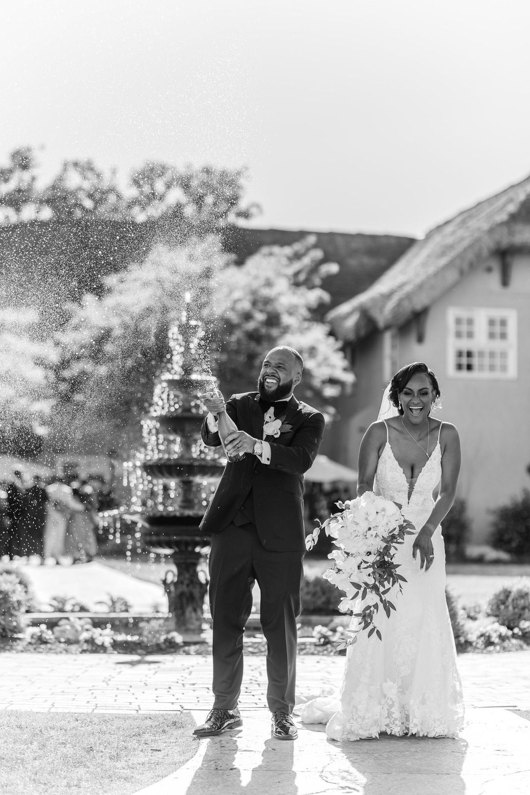 A joyful black and white wedding celebration with a champagne tower in an outdoor garden setting.