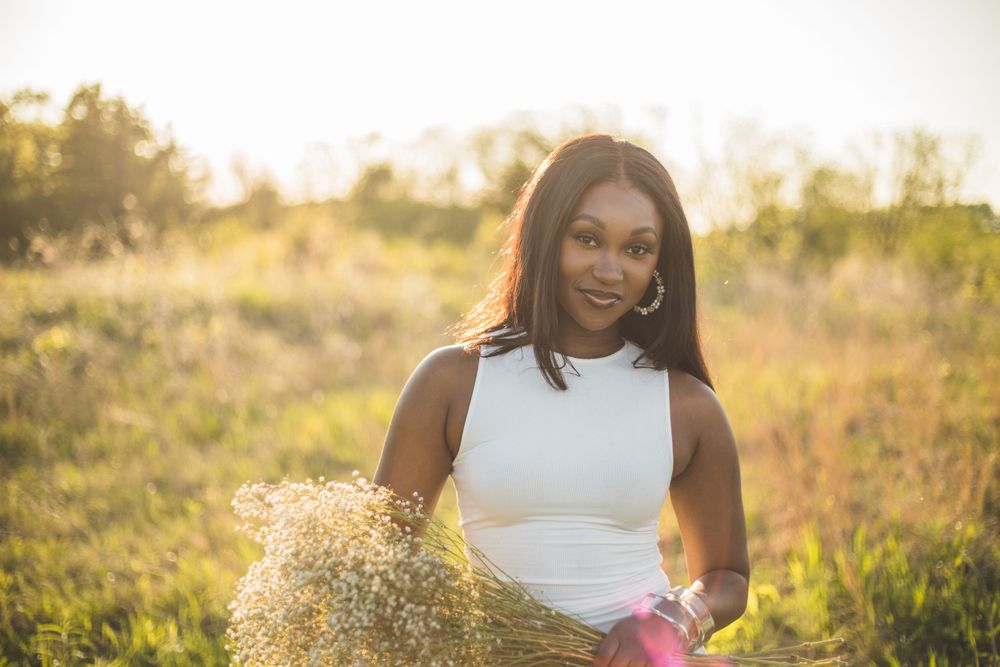 Woman in white dress holding wildflowers during golden hour in a field.