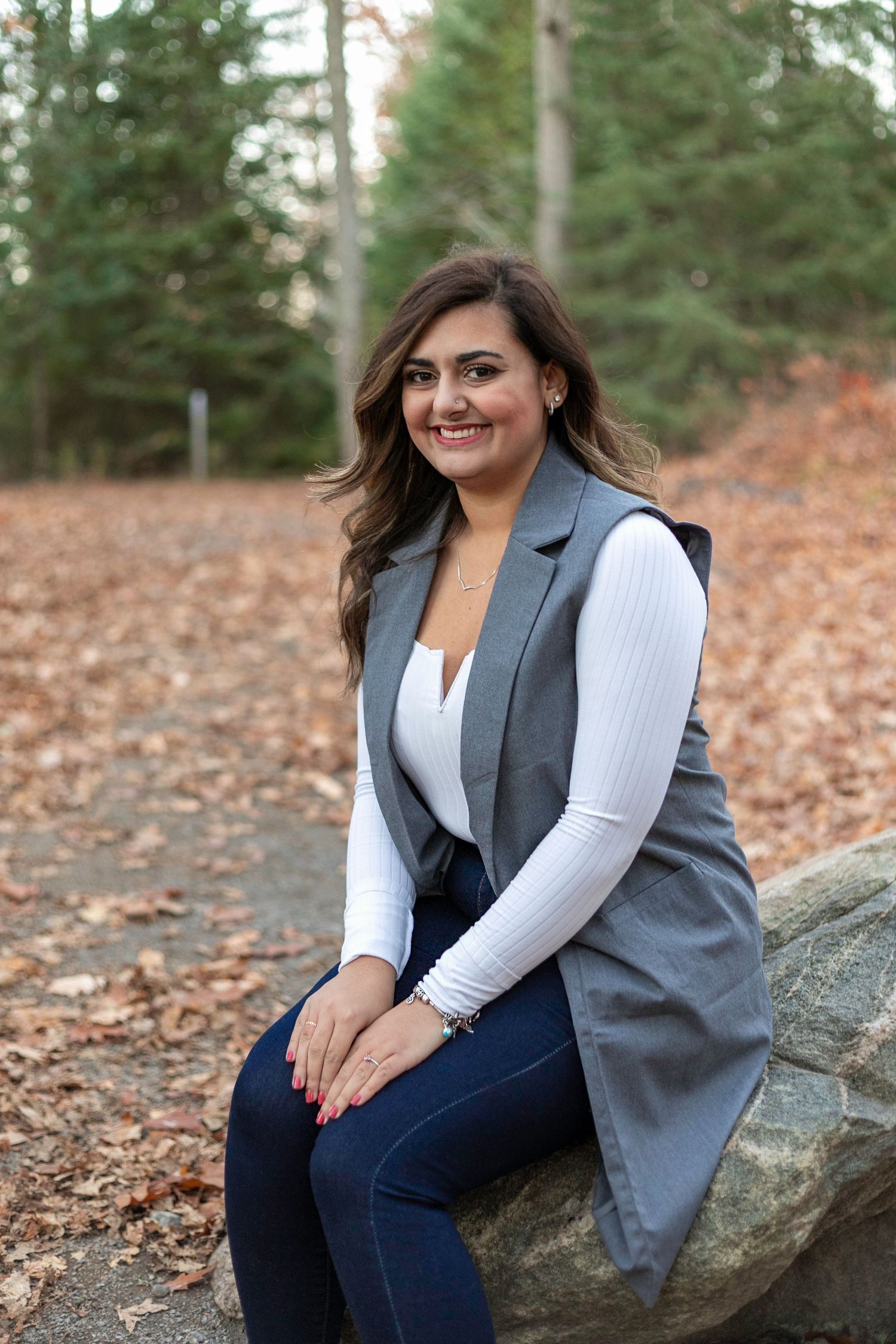 Woman sitting on rock smiling at Heber Downs Conservation area in Whitby, posed.
