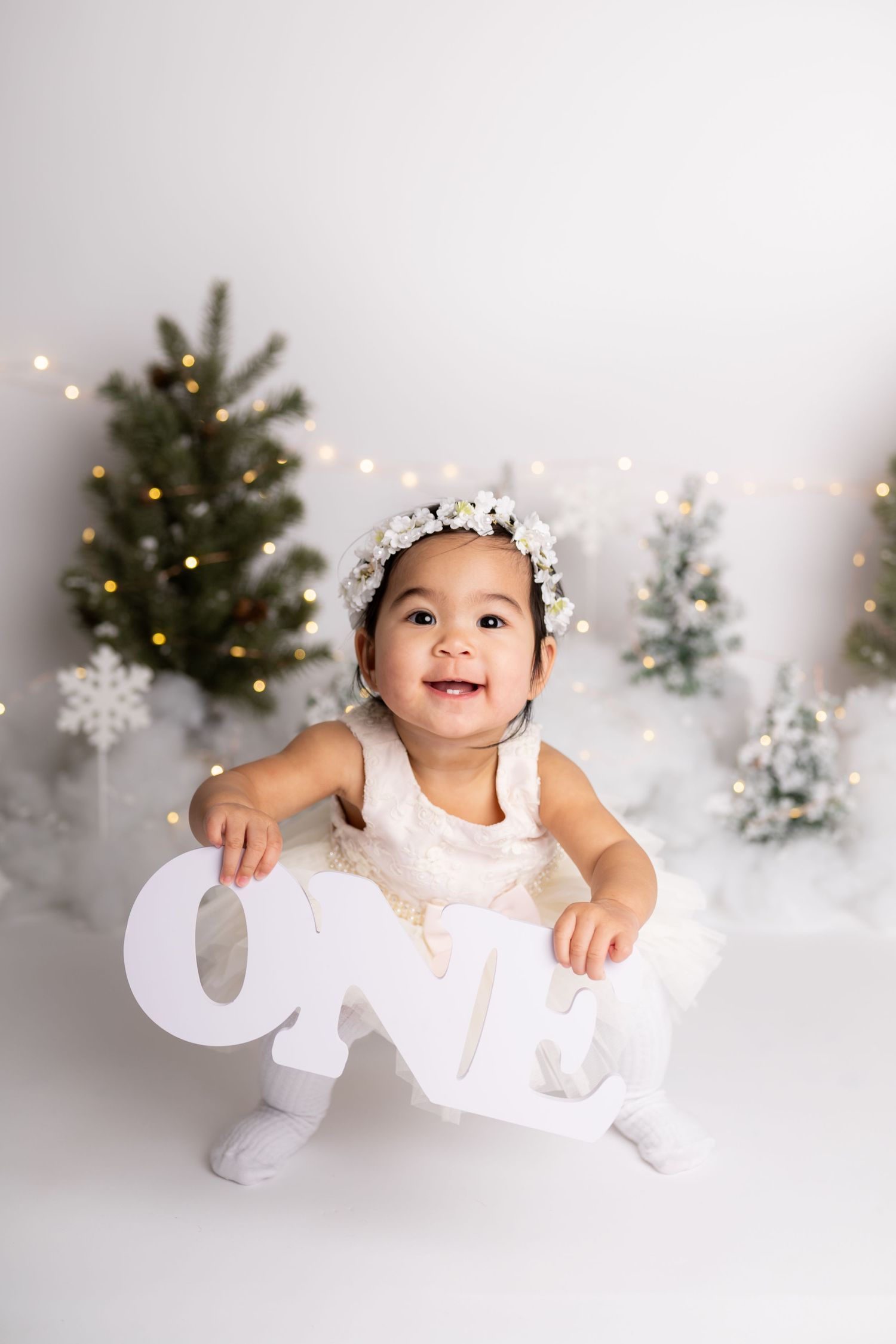 A festive holiday photo setup with decorated Christmas trees and twinkling lights in the background.