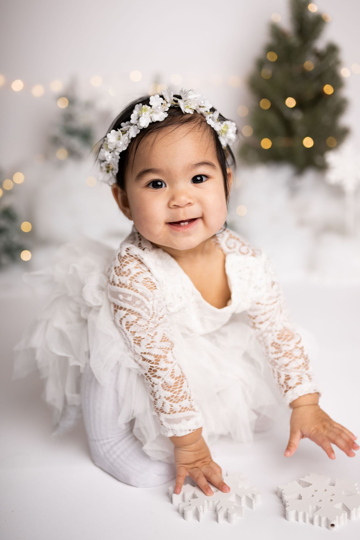 A sweet winter portrait setup with Christmas trees, string lights, and white decorative snowflakes.