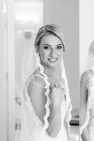 Portrait of a bride wearing a delicate lace veil in black and white.