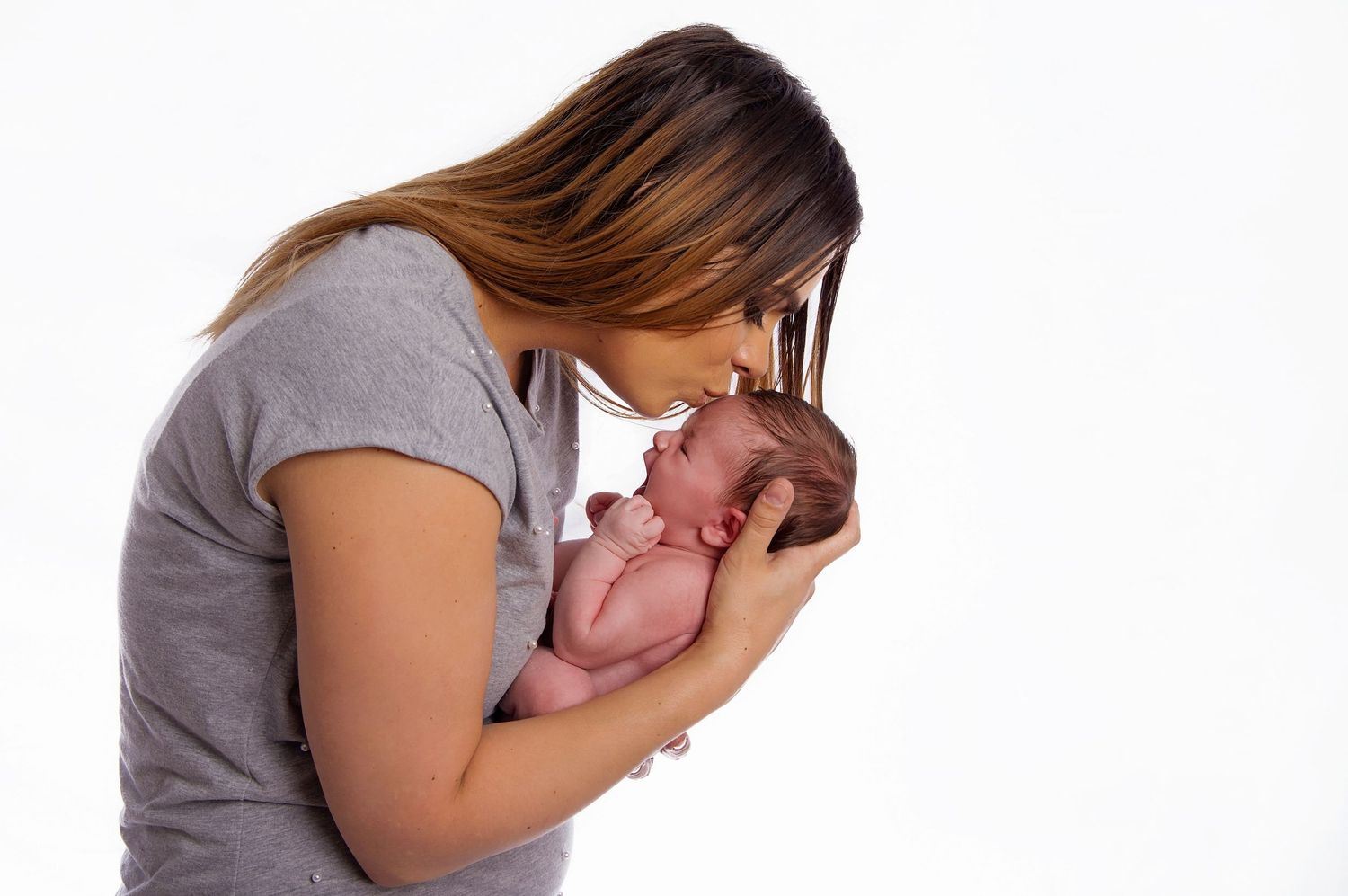 mother kissing newborn baby on forehead