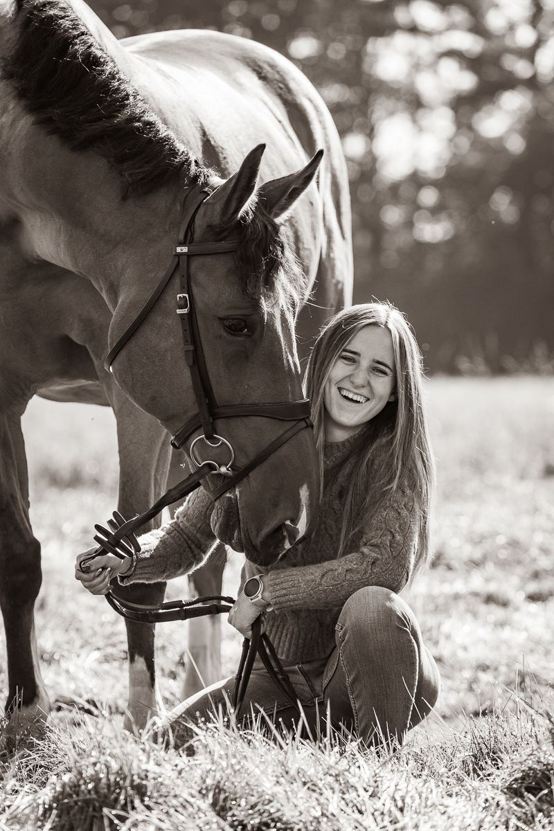 Horse and companion sharing a tender moment in a sunlit meadow captured in black and white.