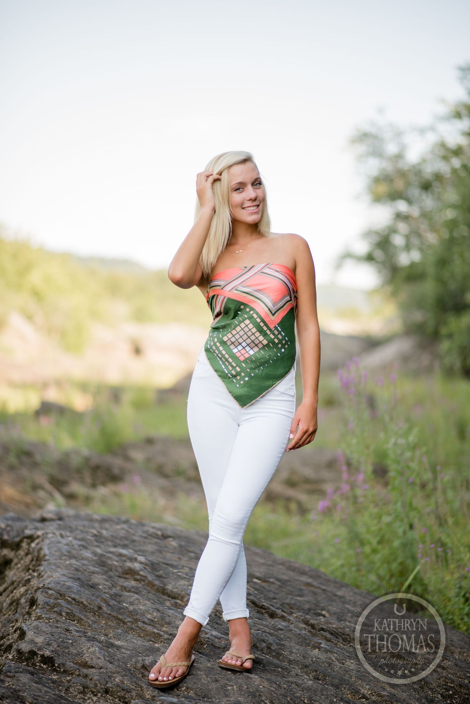 Casual outdoor photo with someone wearing geometric print top and white pants on rocky terrain.