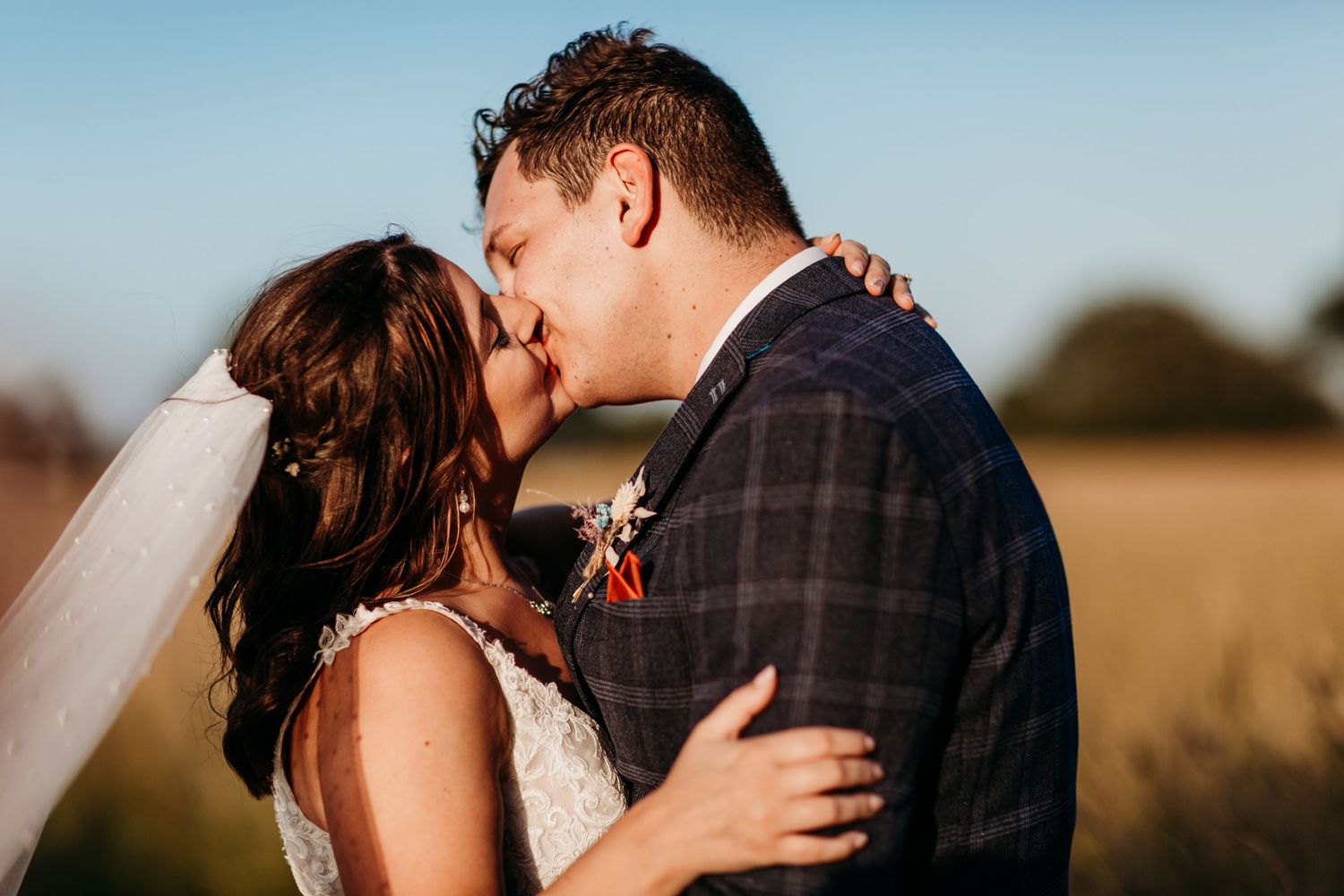Intimate wedding portrait of a couple sharing a romantic kiss in formal attire.