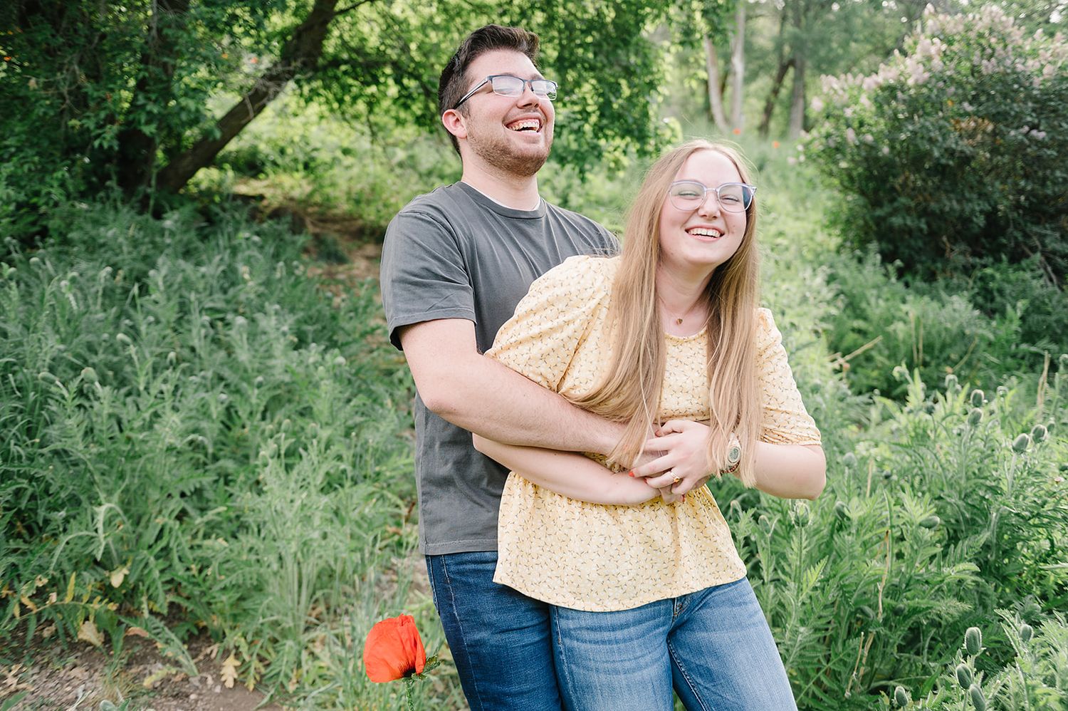 A candid laughing moment captured in a lush green natural setting.